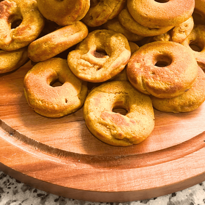 1. Baked mini bagels with golden crust on wooden serving tray.
